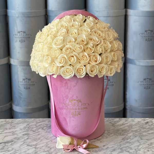 Cream rose bouquet in a pink hat box with a small wrapped cone favor in front