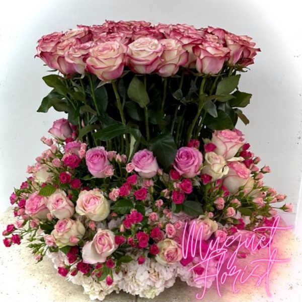 Tiered pink and white rose arrangement with dense greenery