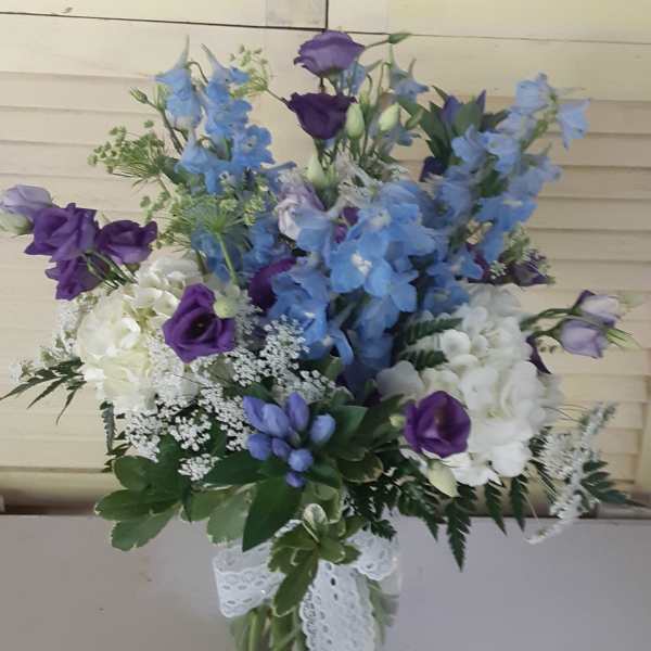 Blue and purple mixed bouquet in a glass vase with a lace ribbon