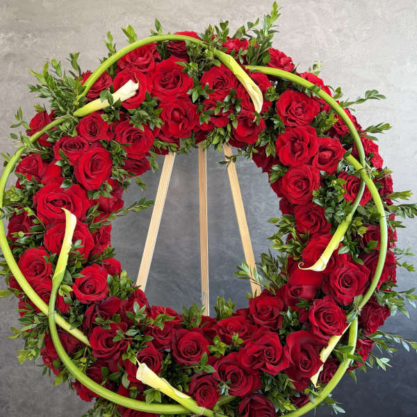 Circular wreath of red roses with white calla lilies on an easel