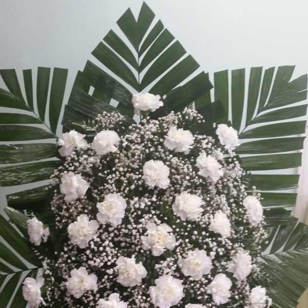 White carnation standing spray with palm fronds