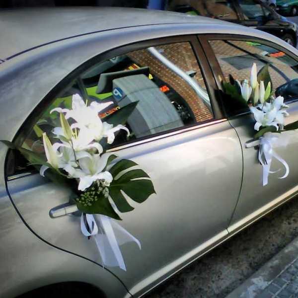 White lilies with ribbons attached to a silver car