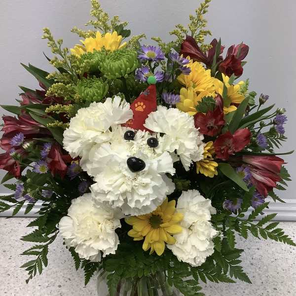 Colorful bouquet with a dog face made of white carnations in a glass vase
