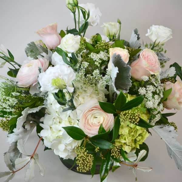 Pastel roses and white blooms arranged in a low vase