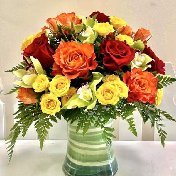 Bouquet of red, orange, and yellow roses in a striped glass vase