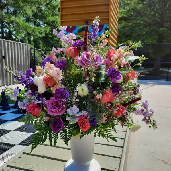 Large mixed floral arrangement in a white pedestal vase