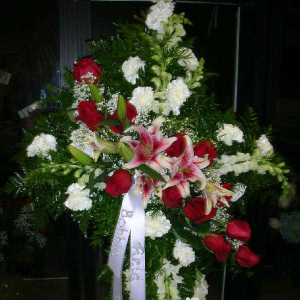 Standing floral spray with red roses, pink lilies, and white blooms