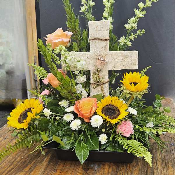 Cross-shaped floral arrangement with sunflowers, peach roses, and white blooms