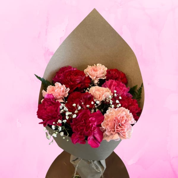 Bouquet of red and pink carnations wrapped in brown paper
