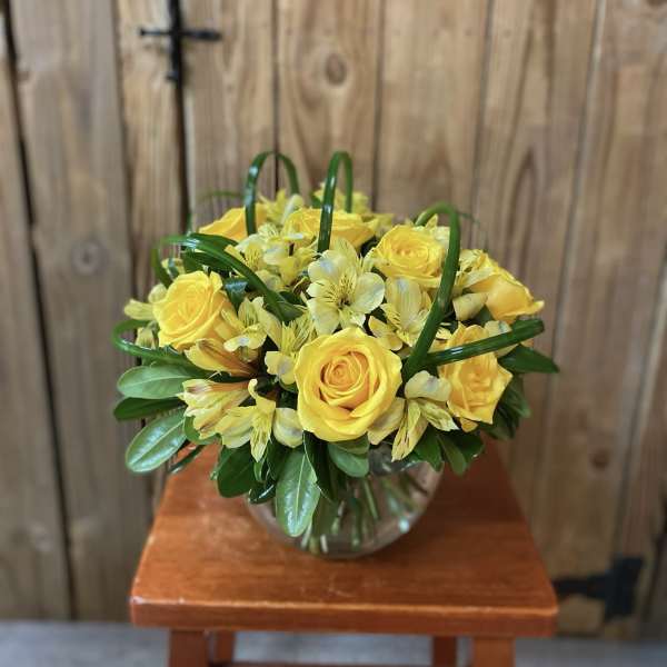 Yellow roses and pale yellow alstroemeria in a glass vase