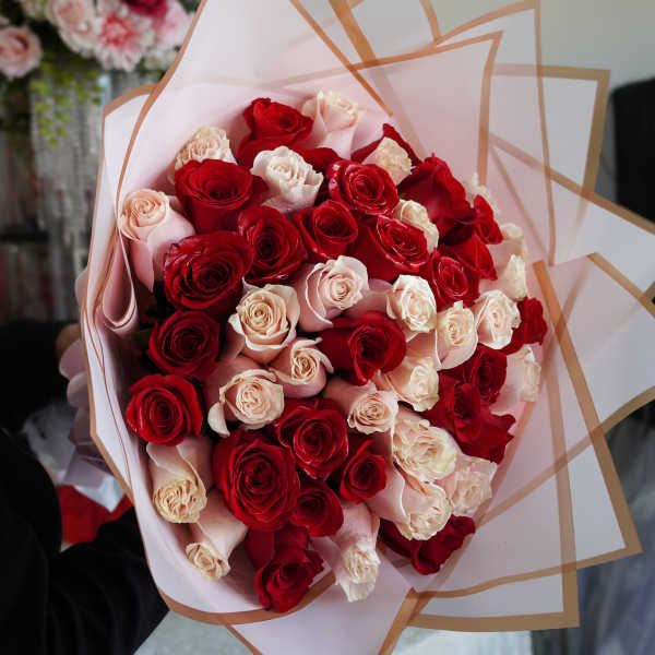Bouquet of red and blush roses wrapped in pale pink paper