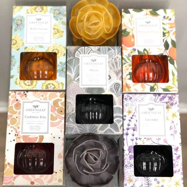 Assorted boxed home fragrance diffusers with floral designs and pumpkin-shaped glass bottles on a shelf