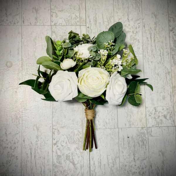 White rose bouquet with mixed greenery on a tiled floor