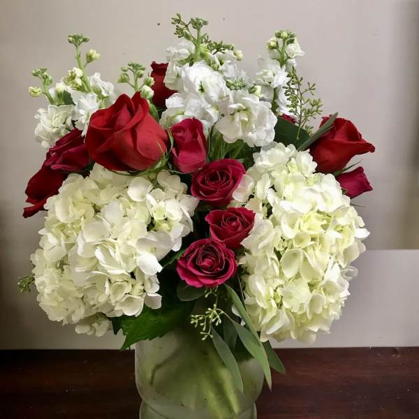 Red roses and white hydrangeas arranged in a glass vase