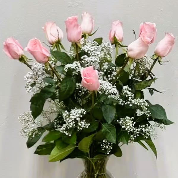 Pink roses arranged in a clear glass vase with white filler flowers
