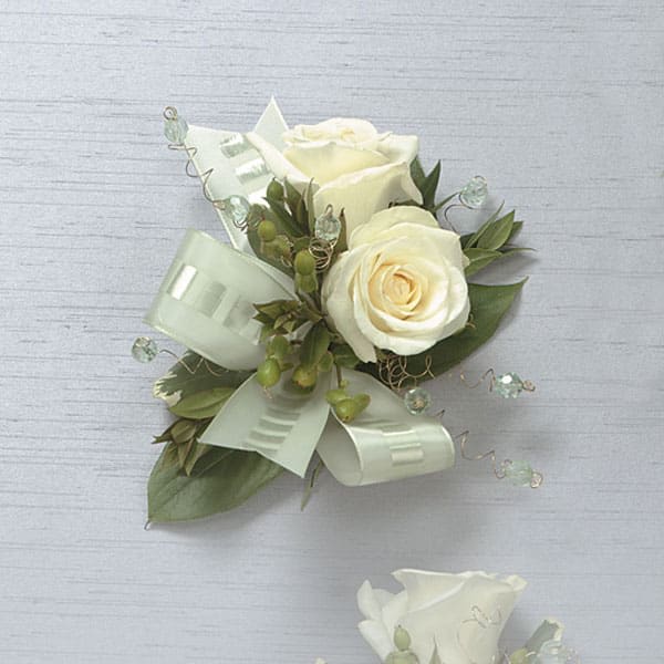 White rose boutonniere with pale ribbon and greenery
