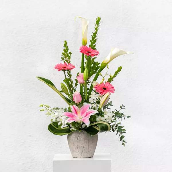 Pink gerberas and lilies arranged in a gray vase