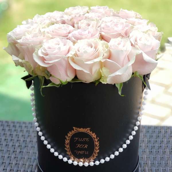 Pale pink roses arranged in a black hatbox with pearl trim