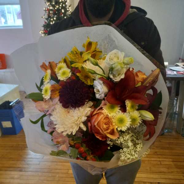 Large mixed bouquet with lilies, roses, and chrysanthemums wrapped in white paper
