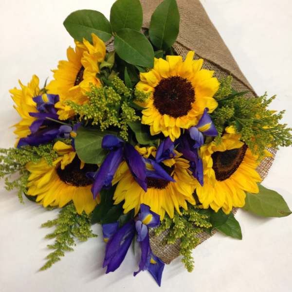 Bouquet of sunflowers and purple irises wrapped in burlap