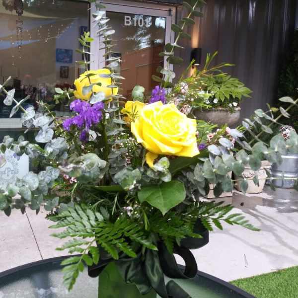 Yellow roses with purple flowers and eucalyptus in a vase