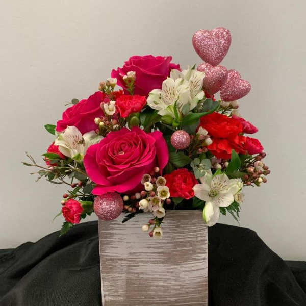 Pink and white flower arrangement in a square box with glitter heart picks