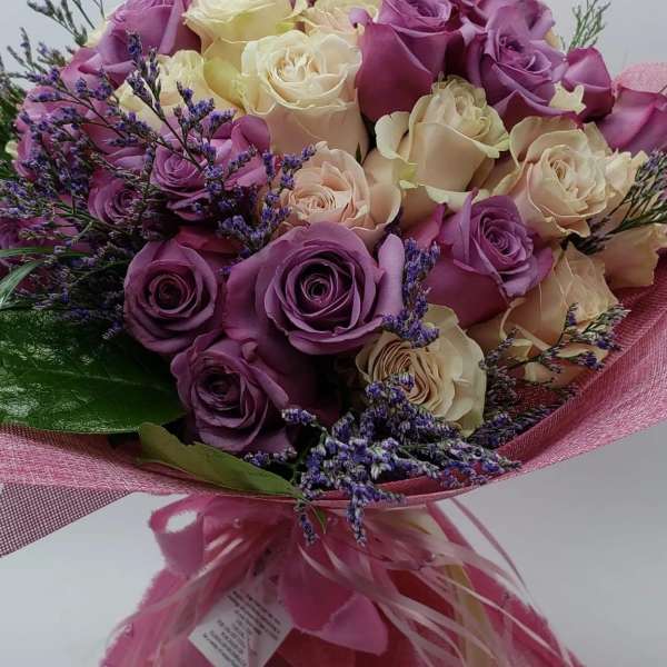 Bouquet of purple and cream roses with pink wrapping