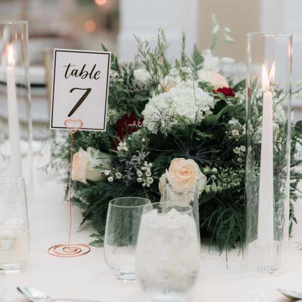 White and blush floral centerpiece with table number and tall candles
