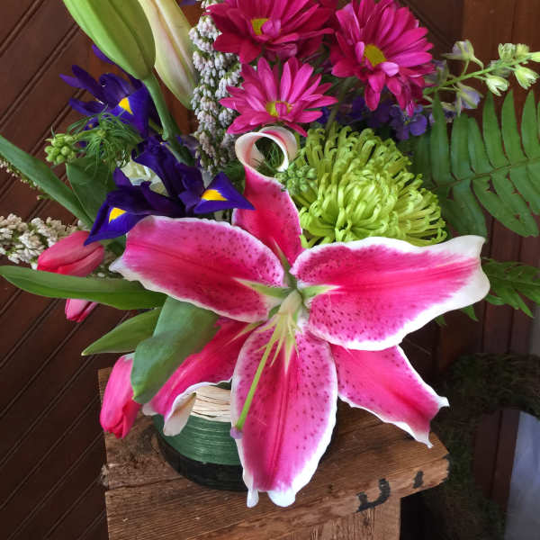 Bouquet with pink lilies, magenta daisies, and purple iris in a vase