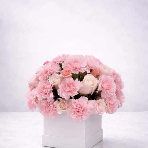 Pink carnations and pale roses arranged in a white box