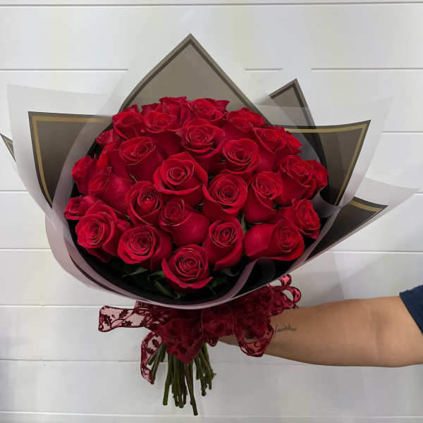 Bouquet of red roses wrapped in black and white paper with a burgundy ribbon