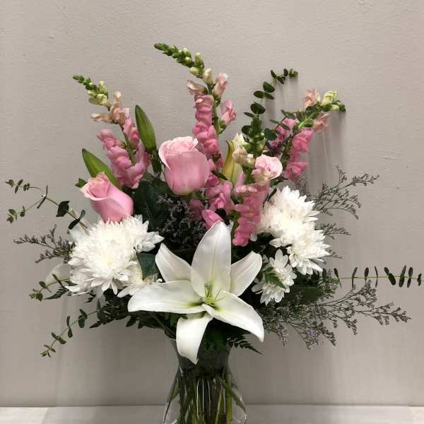 Pink roses, white lilies, and white chrysanthemums in a glass vase