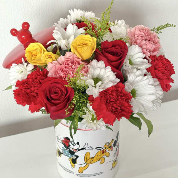 Red, yellow, and white flowers in a Mickey Mouse container with a red balloon topper