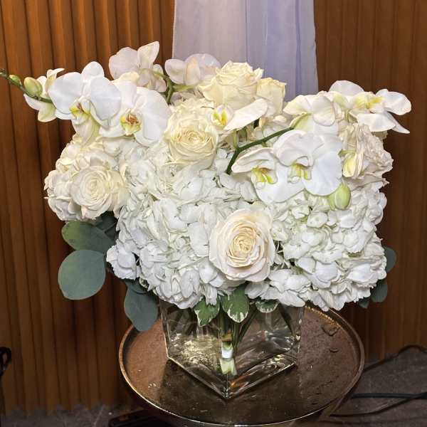 White orchids and roses arranged in a square glass vase