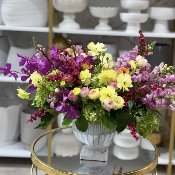 Colorful mixed flower arrangement in a white pedestal vase