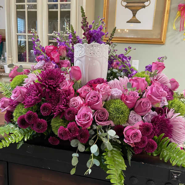 Large pink and purple floral arrangement in a white vase