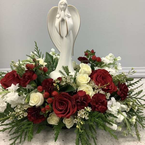 Red and white rose arrangement with a praying angel statue