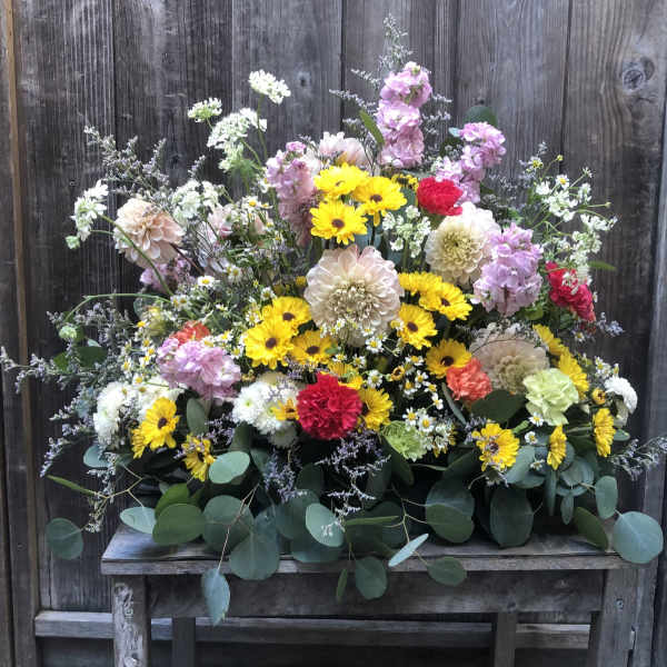 Mixed bouquet of yellow, pink, white, and red flowers on a wooden table