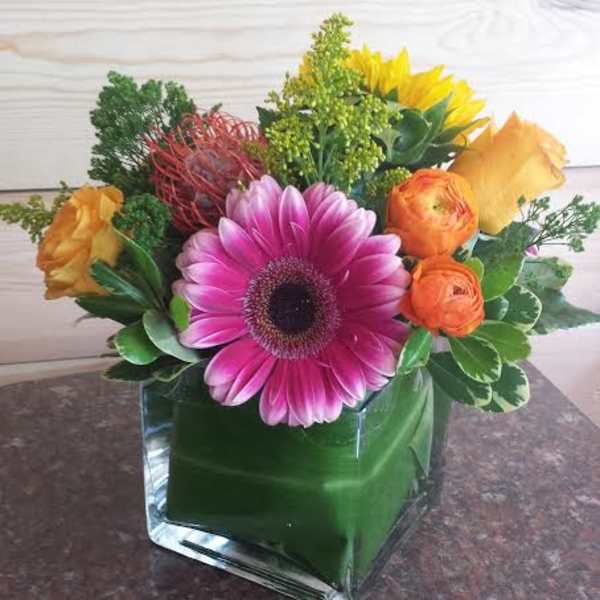 Colorful bouquet with a pink gerbera daisy in a glass cube vase