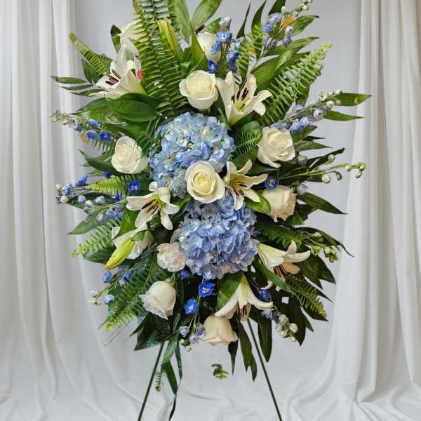 Standing floral spray with white roses, lilies, and blue hydrangeas