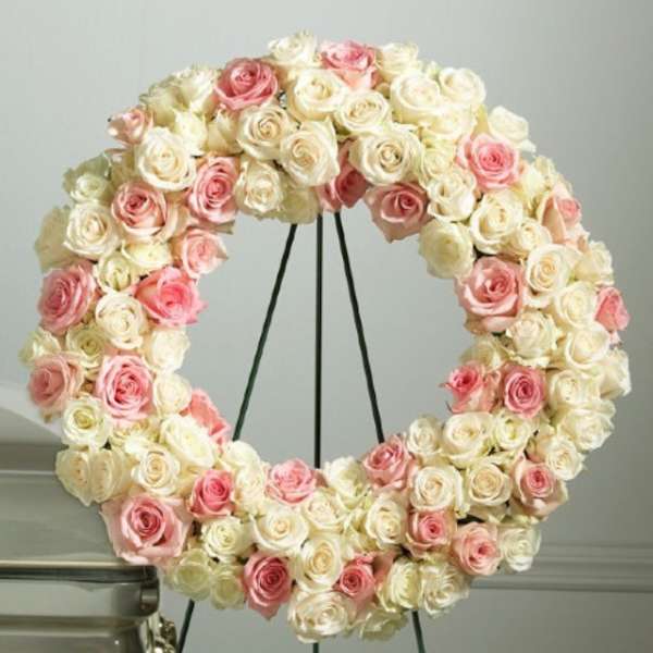 Circular wreath of pink and white roses on a stand