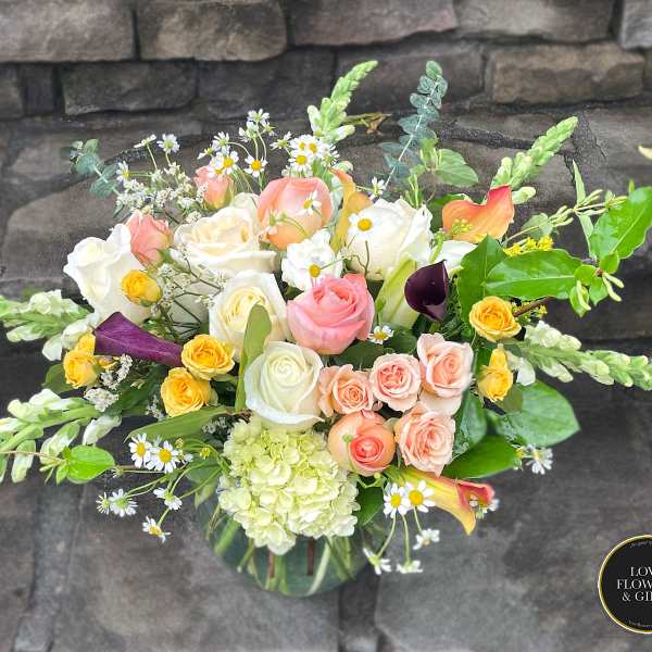 Pastel rose and mixed flower arrangement with snapdragons and calla lilies in a clear glass vase