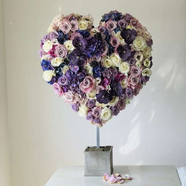 Heart-shaped floral arrangement of roses and hydrangeas on a stand