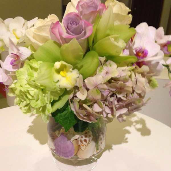 Bouquet of roses, orchids, and hydrangea in a clear glass vase