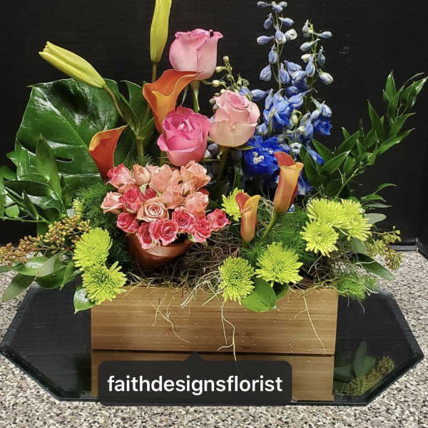 Mixed floral arrangement with roses, calla lilies, and blue delphinium in a wooden box