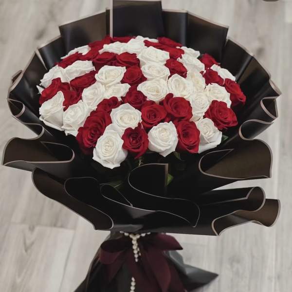 Bouquet of red and white roses wrapped in black paper