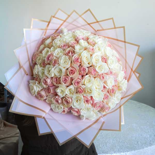 Large bouquet of white and blush pink roses wrapped in pale pink paper