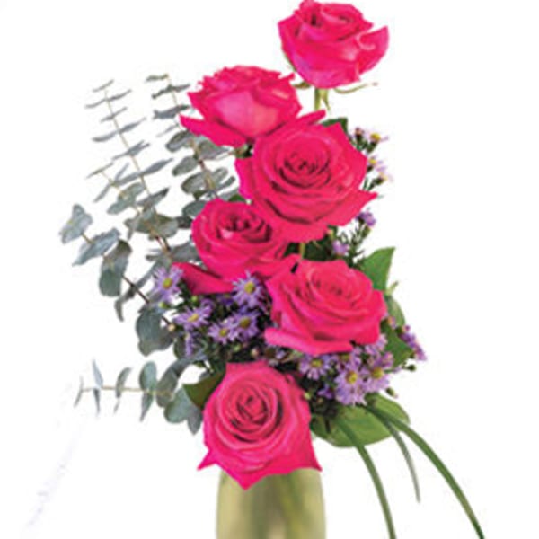 Pink roses arranged in a tall glass vase with purple filler flowers