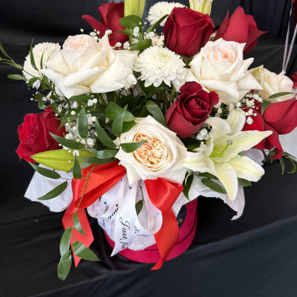 Bouquet of red and white roses with lilies in a pink hat box