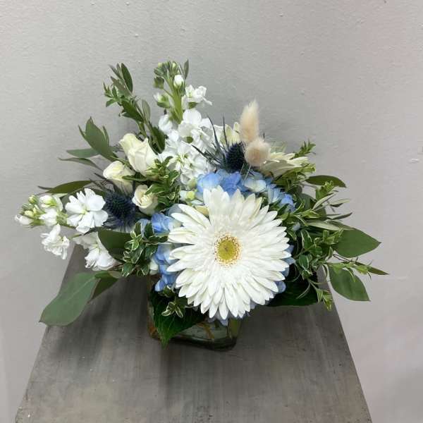 White and blue floral arrangement in a glass vase